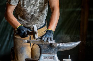 Bir demirci at nalı ile çalışıyor.