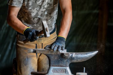 Bir demirci at nalı ile çalışıyor.