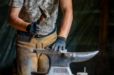 Bir demirci at nalı ile çalışıyor.