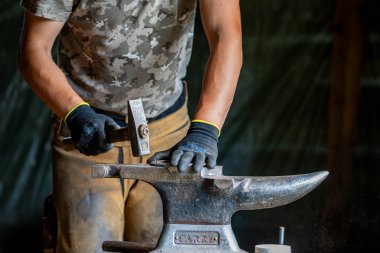 Bir demirci at nalı ile çalışıyor.