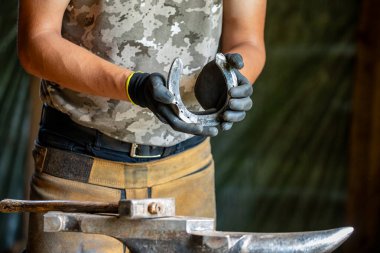 Bir demirci at nalı ile çalışıyor.