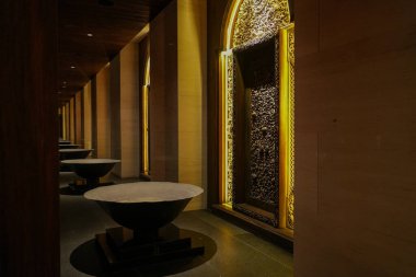 Geleneksel oyulmuş ahşap paneller ile mermer bir masanın modern şıklığı arasındaki zıtlığı gösteren zarif bir iç mekan.