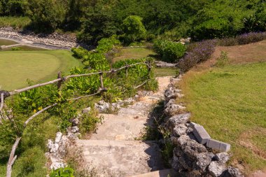 Golf sahasına giden ahşap parmaklıklı taştan basamaklar, yemyeşil ve canlı çiçeklerle çevrili, golfçülere huzurlu ve huzurlu bir yol sunuyor..