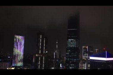 Malezya, Kuala Lumpur, 05.15.2024 - Yıldırımlı bir yağmur fırtınası sırasında çarpıcı bir gece manzarası. Aydınlatılmış gökdelenler yağmur sahnesine dramatik bir dokunuş ekler..