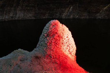 Turda, Romanya, 20 Ekim 2024: Salina Turda içinde bir tuz oluşumu, tarihi madenin doğal dokusu ve jeolojik özelliklerini vurgulayarak sıcak kırmızı ışıkla aydınlatıldı.