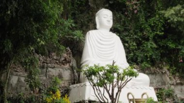 Vietnam, Da Nang 'daki yemyeşil yemyeşil bir yerde huzur içinde duran dingin beyaz Buda heykeli doğal güzelliklerle çevrili huzuru ve manevi yansımayı simgeliyor..