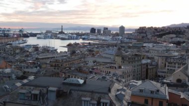 Gün batımında Cenova 'nın liman ve şehir manzarasının panoramik görüntüsü. Tarihi binalar, lüks yatlar ve şehir silueti günbatımına karşı dinamik bir karışım oluşturuyor. Seyahat ve mimari temalar için ideal.