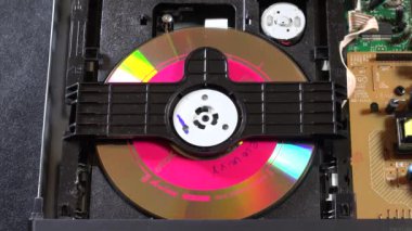 Açık bir DVD oynatıcı, çeşitli açılardan görülen disk yükleme ve boşaltma hareketleri ile dahili bileşenlerini ve devrelerini gösterir. Bu resim ev eğlence sistemlerinin teknolojisini ve tasarımını vurgular.