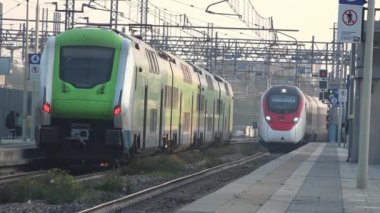 Milan, İtalya, 15 Kasım 2024: SBB-FFS Giruno treni Milan Forlanini istasyonunda Trenord Hitachi treniyle buluşur ve modern ulaşımın özünü yakalar. Görüntü şehir altyapısını ve gelişmiş demiryolu teknolojisinin gücünü gösteriyor.