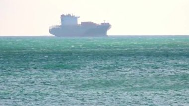 Genova 'nın önündeki Ligurian Denizi' nde ilerleyen büyük bir kargo gemisi. Parlak bir gökyüzü ve dalgalı bir denizin altında.