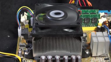 Devre kartındaki bir bilgisayar vantilatörünün detaylı yakın çekimi, karmaşık elektronik parçalar ve renkli kablolar sergiliyor. Teknoloji ve mühendislik kavramları için ideal. Soğutma sistemine ve donanım bakımına odaklan.