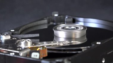 Veri depolama ve işlevsellik için gerekli karmaşık mekanik parçaların vurgulandığı, dönen bir sabit diskin iç bileşenlerini gösteren ayrıntılı bir yakın çekim resmi.