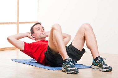 Beyaz adam spor salonunda kırmızı tişört ve diğer aksesuarlarla spor yapıyor.. 