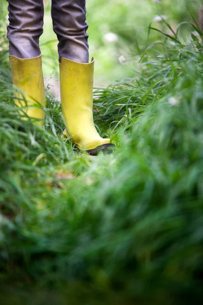 stock image Legs of a boy in green wellies in the middle of the grass. 