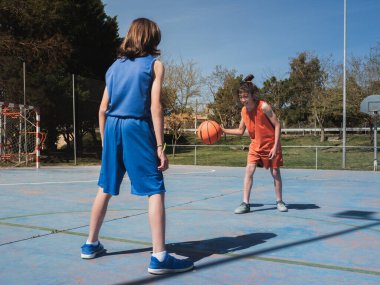 Güneşli bir günde açık hava sahasında iki genç basketbolcu arasında bire bir..