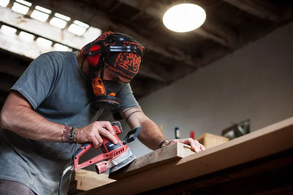 In the bustling workshop, a skilled woodworker is captured polishing a board with a random orbital sander. The image showcases the artisan\'s craftsmanship, while offering abundant copy space for personalized messages or branding.