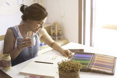 Ressam kahve molası verirken işine mutlu bir şekilde bakıyor.. 