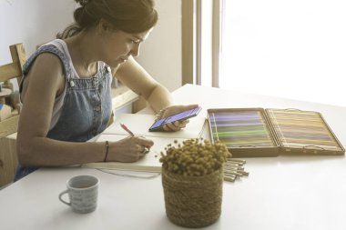 Illustrator ilham kaynağı olarak cep telefonunu kullanıyor ve çalışmalarını yürütmek için referans alıyor.. 