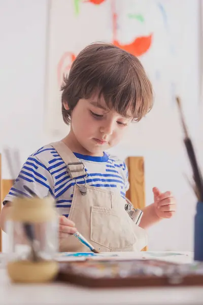 Çocuk fırçasıyla sanat eserlerini boyuyor..