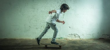 Endüstriyel bir ortamda kaykayıyla dolaşan bir çocuk..