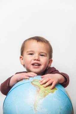 Little boy comes out from behind a world ball looking at the camera. copy space above his head. clipart