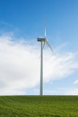 Yeşil bir çayırdan çıkan elektrik üretimi için dikey yel değirmeninin fotoğrafı. sürdürülebilir geliştirme. 