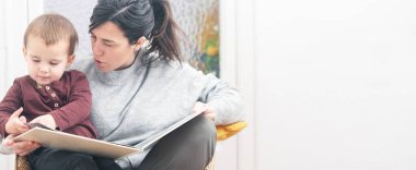 Bir annenin çocuğuna masal okuduğu ve kitabın sayfalarını çevirdiği bir panoramik..