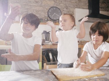 Kardeşler pasta yaparken unla oynuyorlar.