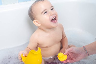 Küvette gülümseyen küçük bir çocuk.