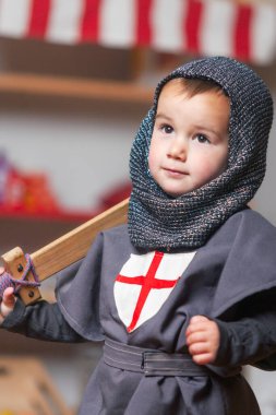 Omzunda tahta kılıcıyla şövalye gibi giyinmiş bir çocuğun portresi..