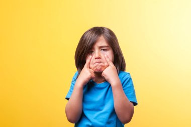 Uzun kahverengi saçlı, üzgün yüzlü ve parmaklı bir çocuk. 