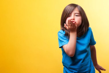 Kahverengi saçlı bir çocuk kameraya bakarak öpücük yolluyor ve mavi gömlek giyiyor. Şefkat, sevgi, şefkat kavramı. Boşluğu kopyala. 
