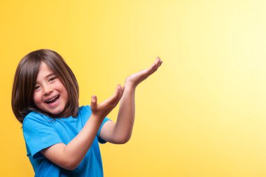 Bir çocuk mavi bir gömlek giyiyor ve yüzünde kocaman bir gülümseme var. Elleri görüntünün üzerine mesaj ya da logo koymak için açık. Boşluğu kopyala. 