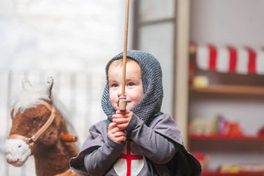 Oyun odasında elinde kılıçla şövalye gibi giyinmiş bir çocuk. Oyun, eğitim, sembolik oyun. 