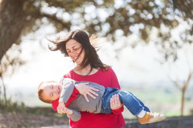 Kollarında çocuğuyla yuvarlanan bir kadın. Mutlu ve gülümseyen bir aile. 