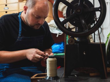 Ayakkabıcı bir ayakkabıyı tamir etmek için dikiş makinesi hazırlıyor. Ticaret ve endüstri
