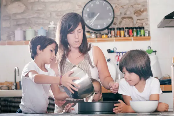 Anne ve çocuklar mutfakta pasta hazırlarken hamuru kalıba dökün.. 