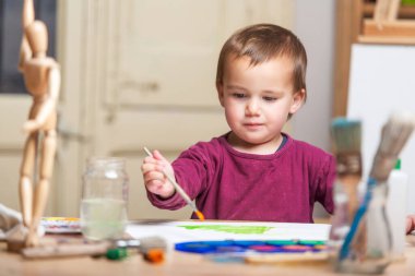 Evdeki oyun odasında sanatsal bir aktivitenin keyfini çıkaran küçük bir çocuk. Sanat ve resim