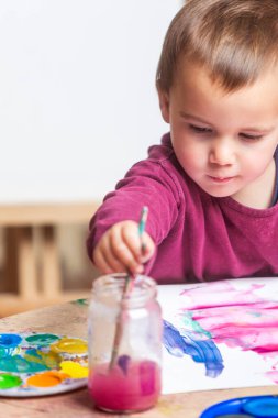 Yürümeye başlayan fırça, beyaz kağıda suluboya sürmek için suya batırılmış.. 