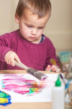 Suluboya ve boş bir kağıt parçasında büyük bir boya fırçası ile yürümeye başlayan bebek deneyleri.. 