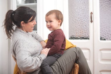 Anne ve küçük çocuk evlerinin oturma odasındaki bir koltukta dinlenirken hassas bir anı paylaşıyorlar. Annelik kavramı. 