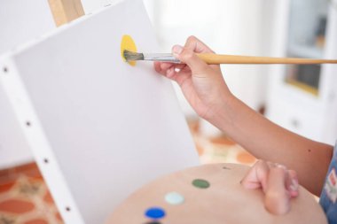 Çocuğun ellerini tuvale fırçayla boyayıp paleti tutarken yakın plan. Sanat ve hobi kavramı. 