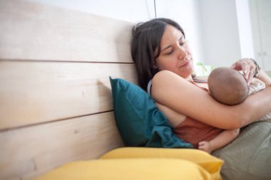 Anne, yeni doğmuş kızını şefkatle kollarında uyurken seyrediyor. Boşluğu Kopyala. 