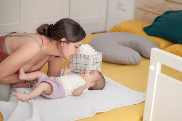 Anne ve yeni doğan kızı arasında hassas bir an. Yatak odasındaki yatakta bezini değiştirmeden hemen önce.. 