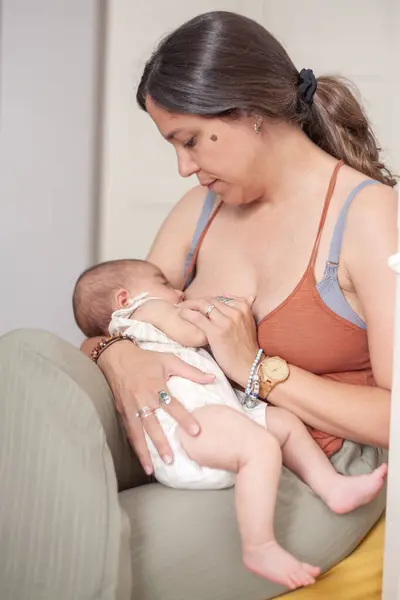 Bir kadın yatak odasındaki yatakta otururken bebeği emziriyor.. 