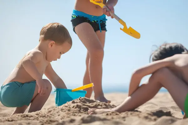 Bebekleri ve kardeşleri kumsalda kumla oynuyorlar.. 