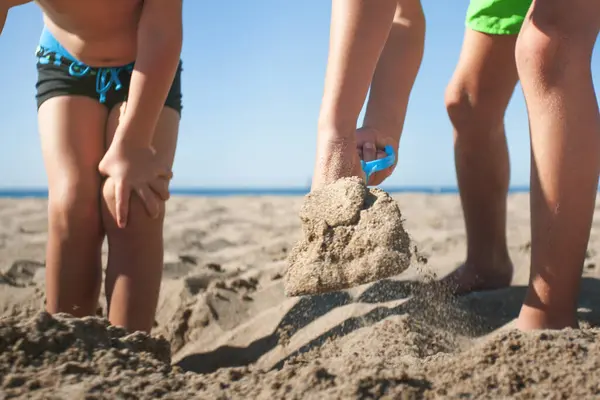Kum küreyerek delik açan tanınmayan çocukların el ve bacaklarına yakın çekim.. 