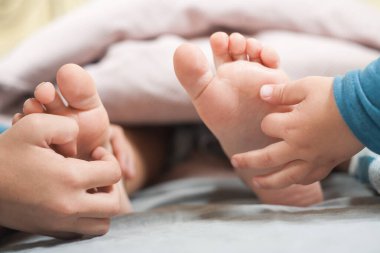 Yatakta yorganla kaplı bir çocuğun ayaklarının yakın çekimi. Ama ayakları dışarıda ve diğer çocukların elleri ayaklarının tabanını gıdıklıyor..