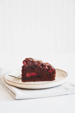 Beyaz ahşap masada kirazlı çikolatalı kek.