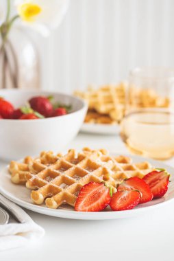 Çilekli Belçika waffle 'ları ve beyaz tabakta pudra şekeri. Kahvaltı konsepti.